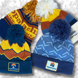 Three colorful beanies with pom-poms on a snowy background, featuring the Appalachian Mountain Company logo.